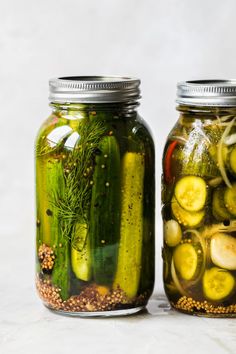 two jars filled with pickles and cucumbers