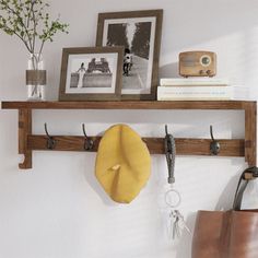 a wooden shelf with hooks and pictures on it next to a brown bag, purse and other items