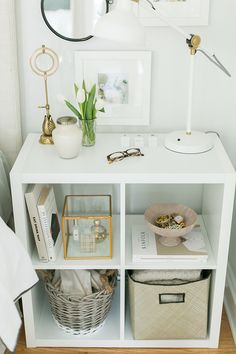 a white shelf with some pictures and other items on top of it in front of a mirror