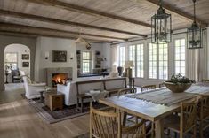 a dining room table with chairs and a fire place in the center is surrounded by windows