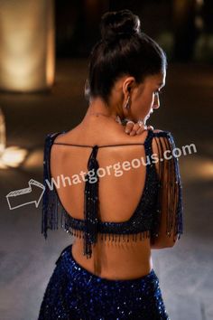 the back of a woman wearing a blue dress with fringes and beads on it