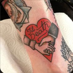 a person with tattoos on their legs holding a heart