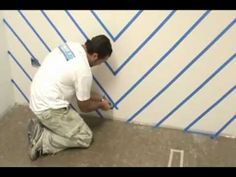 a man in white shirt and khaki pants kneeling on floor next to wall