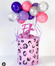 a pink cake topped with lots of balloons