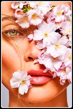 a woman with flowers in her hair and eyes on her face, looking at the camera