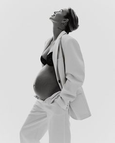 a black and white photo of a woman in a suit with her hands on her hips