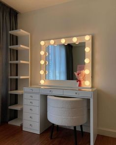 a white vanity with lights on it and a stool in front of the mirror that is lit up