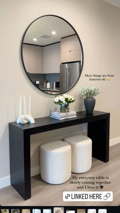 a black table with two stools and a round mirror on the wall above it