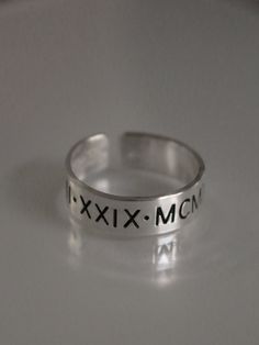 This Roman numeral ring is the perfect piece of personalized jewelry for anniversaries, promise rings and more. Crafted from quality materials, this date ring can be inscribed with custom Roman numerals for a unique piece of jewelry. A great gift for your loved one to commemorate a special occasion. Product Details: Materials: Aluminum, Sterling Silver, Fine Silver, 14k Gold Filled Color: Silver, Gold, Rose Gold Size: 6mm You will receive one hand-stamped ring filled with no enamel finish. Date Ring, Roman Numeral Ring, Stamped Ring, Hand Stamped Ring, Stamped Rings, Roman Numeral, Roman Numerals, Fine Silver, Promise Rings