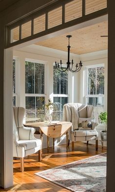 the sun shines through two windows into a living room with chairs and a table