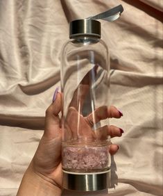 a person holding a glass jar with pink sand inside