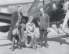 three people standing next to an old airplane