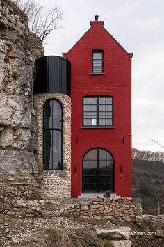 a large red building with black windows next to a stone wall