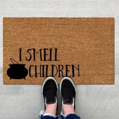 someone standing in front of a door mat that says i smell children