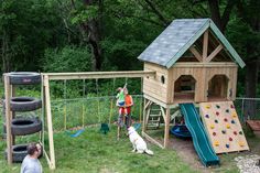 two children playing in a play area with a climbing wall and swing set for dogs