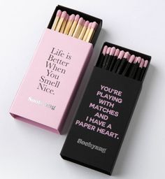 two matches are in a pink box and one is black with white writing on it