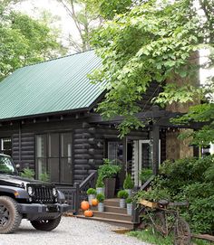 a black jeep parked in front of a log cabin with a green roof and door