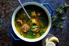 a bowl of soup with cauliflower, lemon and parsley on the side