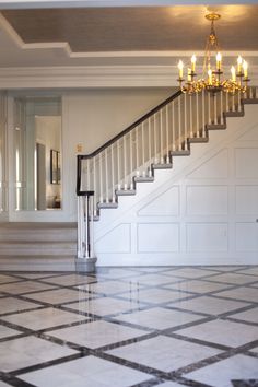 a white staircase with chandelier and tiled floor