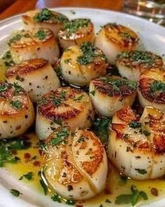 some scallops are on a white plate and garnished with parsley