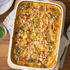 a casserole dish with meat and vegetables in it on top of a wooden table