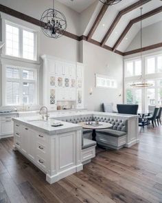 a large open concept kitchen with white cabinets and wood flooring is pictured in this image