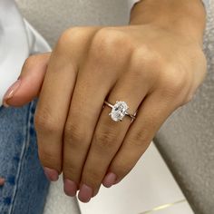 a woman's hand with a diamond ring on her left hand and the other hand holding an engagement ring