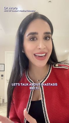 a woman with long hair wearing a red jacket and black top is talking to the camera