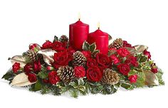 a christmas centerpiece with two red candles and evergreen leaves on it, surrounded by pine cones