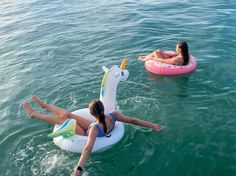 two girls are floating on inflatable unicorns in the water