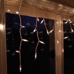 some lights are hanging from the side of a window