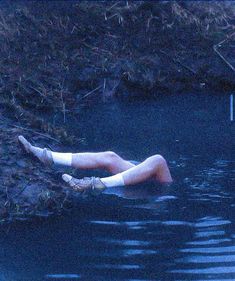 a man laying on his back in the water with no shirt and shorts around him