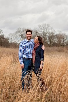 a man and woman are standing in the tall grass with their arms around each other