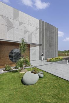 an artistically designed concrete building with two large rocks in the foreground and a palm tree on the other side