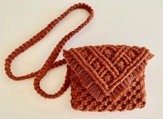 a crocheted brown purse sitting on top of a white table next to a string