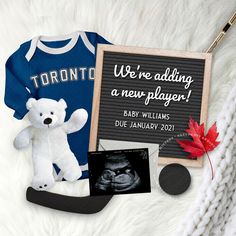 a teddy bear, baby's first year announcement and other items are laid out on a blanket