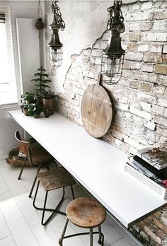 a white table sitting next to a brick wall with potted plants on top of it