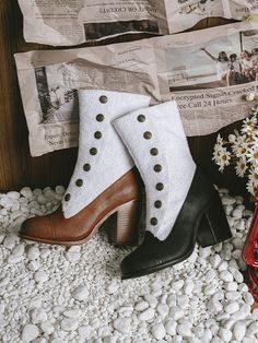 two women's shoes sitting on top of white rocks next to newspaper and flowers