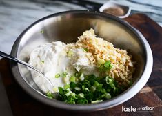 a metal bowl filled with rice and peas on top of a wooden cutting board next to a spoon