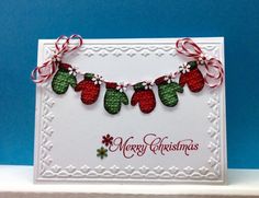 a christmas card with red and green stockings hanging from it's sides on a shelf