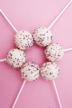 white cake pops with sprinkles on pink background