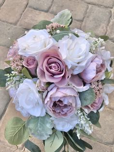 a bouquet of pink and white flowers sitting on top of a brick floor next to a sidewalk