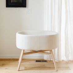 a round white ottoman sitting on top of a hard wood floor next to a window