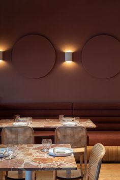 an empty restaurant with tables, chairs and round lights on the wall above them is seen in this image