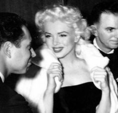 an old black and white photo of marilyn monroe talking to two men in formal wear