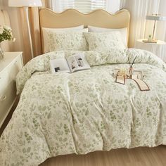 a bed with white and green bedspread in a bedroom next to a window