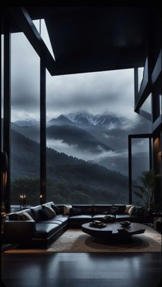 a living room filled with furniture and a large window overlooking the mountains in the distance