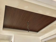 the ceiling in this living room is made out of wood slats and has a metal hook on it