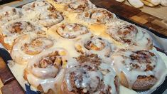 a pan filled with cinnamon rolls covered in icing