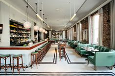 an empty restaurant with green chairs and bar stools